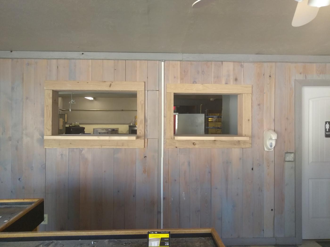 Two framed pass-through openings with new timber sills set into a panelled interior wall
